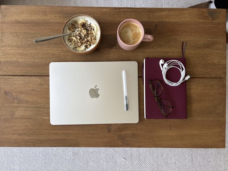 Laptop, schrift, koffie en ontbijt op een houten tafel